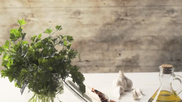 典型的なイタリア料理のスパゲッティ アリオ オリオ ペペロンチーノ ニンニク オイル 唐辛子 の具材の上から下まで 軽い木製のテーブルの上にパセリの小枝とガラス瓶 — ストック動画