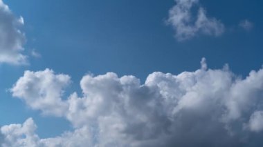 Mavi gökyüzünde soldan sağa dönüp duran beyaz kabarık bulutların zamansız geçişi