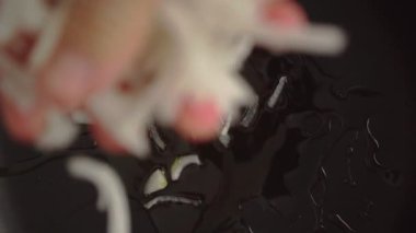 4k yavaş çekim. Aşçının üst görüntüsü. Dilimlenmiş soğanı bokeh etkisi ile kızartma tavasına düşürüyor.