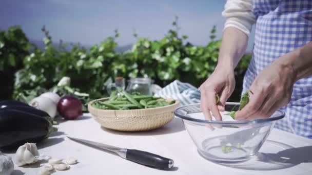 Kvinna Med Förkläde Skal Ärtor Inne Glasskål Utomhus Med Starkt — Stockvideo