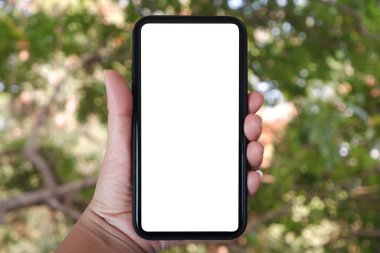 Telefonu dikey tutarak, ağaçların, evin ve bahçenin bulanık arka planına sahip akıllı telefon kullanarak....