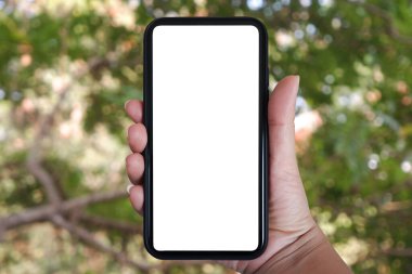 Telefonu dikey tutarak, ağaçların, evin ve bahçenin bulanık arka planına sahip akıllı telefon kullanarak....