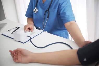 Kadın tıp doktoru danışman bir hastayla masada çalışıyor..