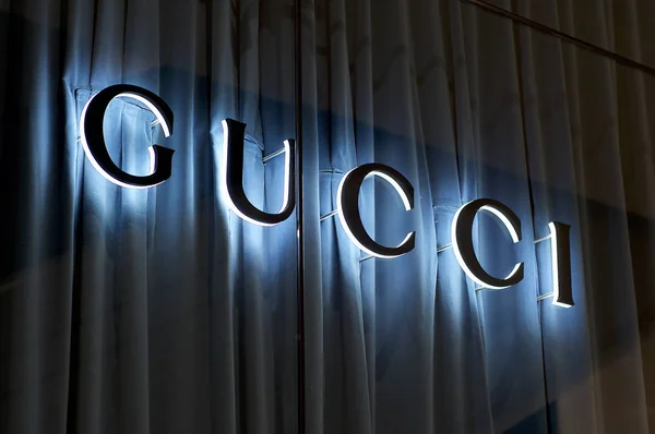Signo de Gucci iluminado con fondo de cortina azul — Foto de Stock
