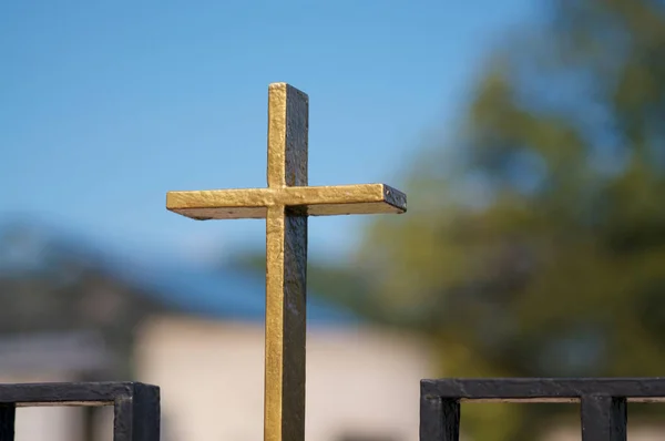 Small metal religious cross against blue sky