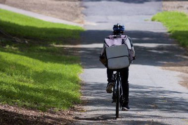 Brisbane 'de bisikletli bir Uber Eats kuryesinin arka görüntüsü. Uber Eats, Uber tarafından başlatılan bir çevrimiçi yiyecek sipariş ve dağıtım platformudur.