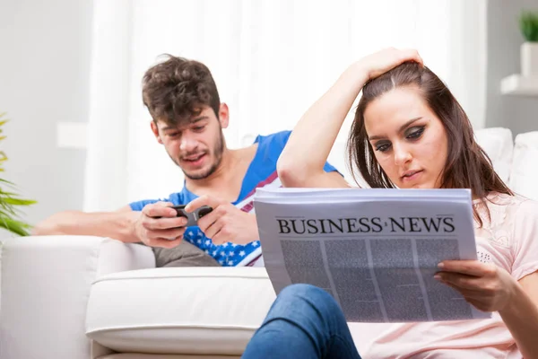 Pareja leyendo uno en papel el otro en su móvil — Foto de Stock