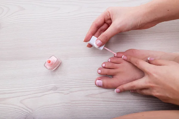 Mão de uma mulher aplicando esmalte rosa — Fotografia de Stock