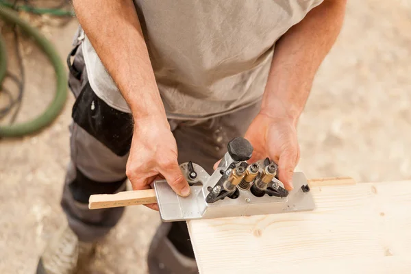 Menuisier tenant un gabarit sur une planche de bois — Photo