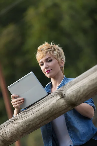 Vrouw met behulp van een laptop-tablet buitenshuis — Stockfoto