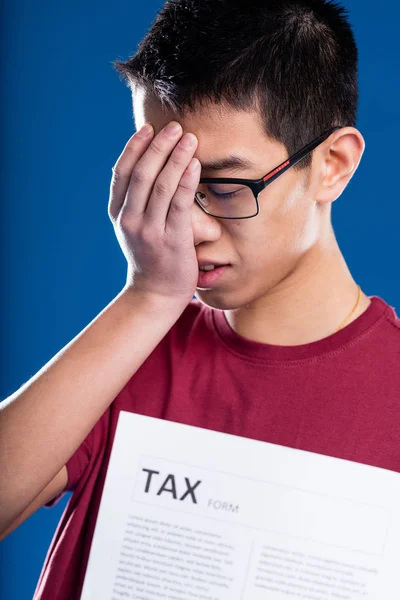 Asian man worried by a tax form — Stock Photo, Image