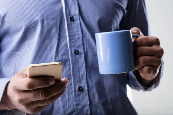 Manos con teléfono inteligente y una taza — Foto de Stock