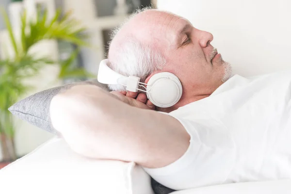 Mature man relaxing with music on the sofa — Stock Photo, Image