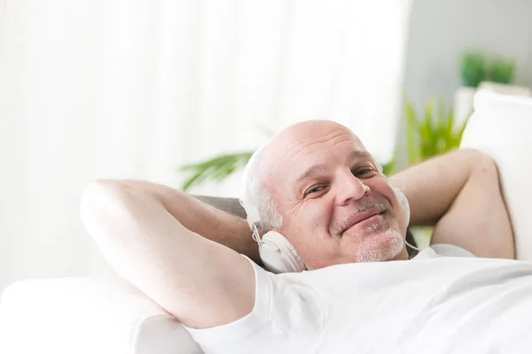 Зрелый мужчина расслабляется с музыкой на диване — стоковое фото