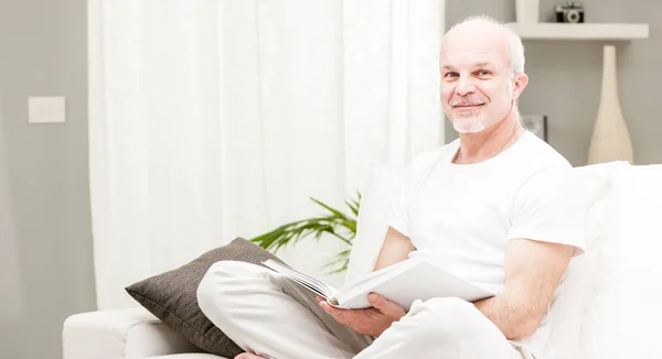 Człowiek czytając książkę w jego salonie — Zdjęcie stockowe