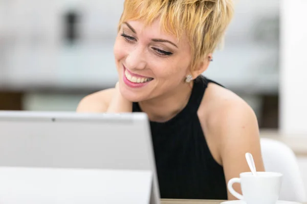 Vrouw die lacht naar een computerscherm — Stockfoto