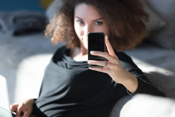 Молодая женщина читает текстовое сообщение на мобильном — стоковое фото