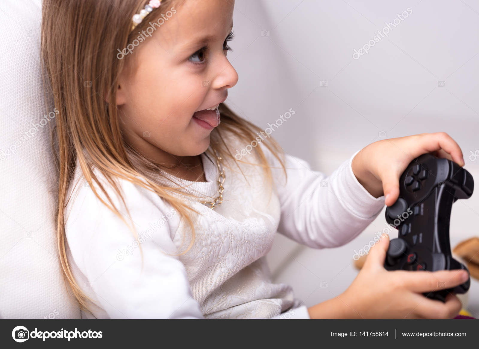 Bambina emozionante divertimento giocare ai videogiochi con il controller di gioco nella mano con la sua linguetta che sporge in concentrazione — Foto di