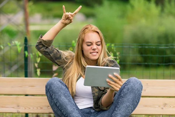 Excited metal lover watching something on her tablet — Stock Photo, Image