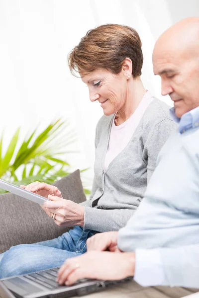 Tech savvy couple with a laptop and tablet — Stock Photo, Image