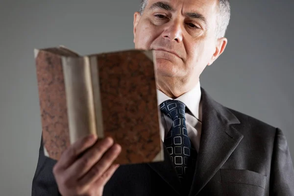 Portrait of a senior man reading from an old book — Stock Photo, Image