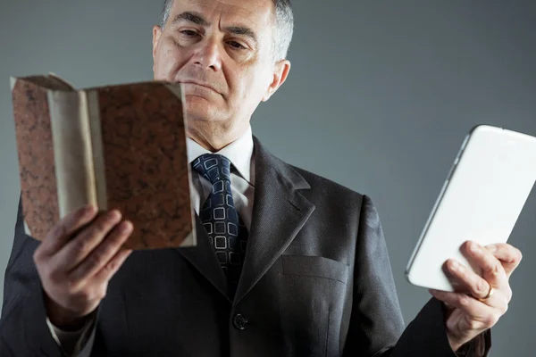 Businessman deciding between a book or e-book — Stock Photo, Image