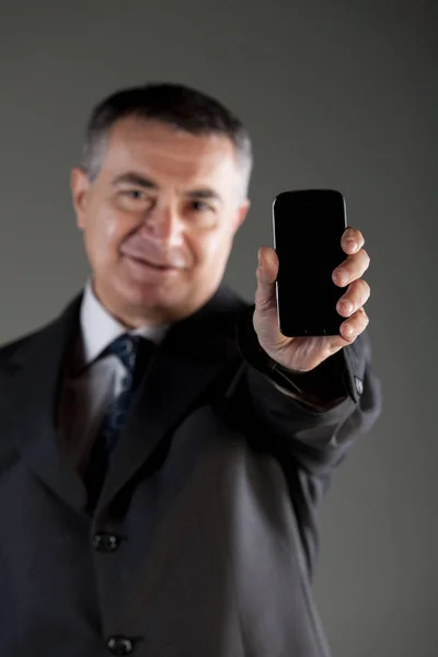 Empresário segurando um telefone celular em branco — Fotografia de Stock