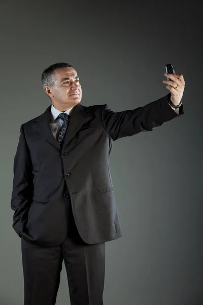 Hombre mayor usando traje mientras se toma una selfie — Foto de Stock