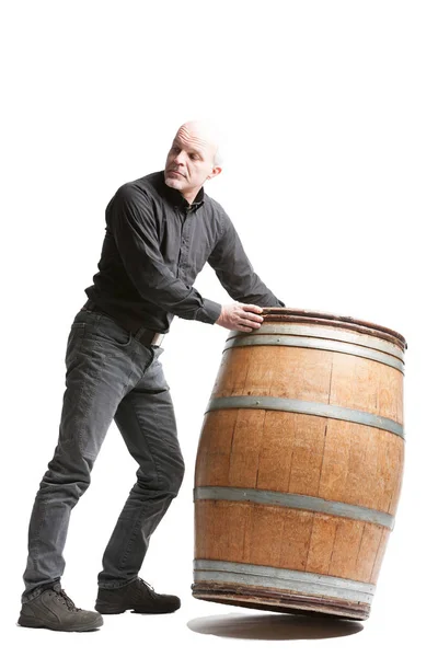 Middle-aged man tilting a wooden cask or barrel — Stock Photo, Image