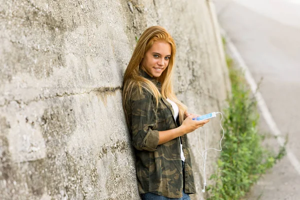 Flicka utomhus med en mobil som undersöker camer — Stockfoto