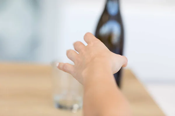 Female hand reaching after bottle — Stock Photo, Image