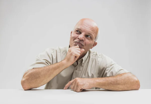 Pleased man sitting thinking with a smile — Stock Photo, Image