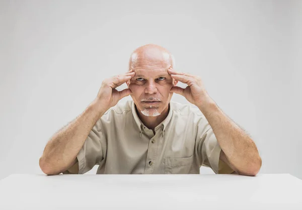 Homme chauve contemplatif assis à table — Photo