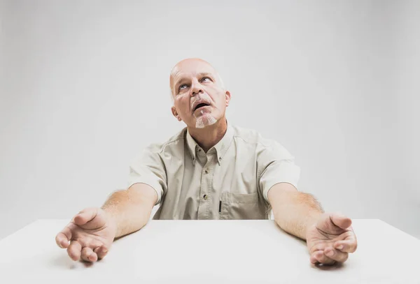 Benadrukt senior man imploringly opzoeken — Stockfoto