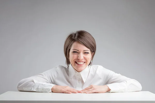 Mujer riendo calurosamente sobre un fondo gris — Foto de Stock