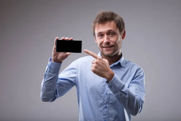 Lachende Vriendelijke Man Wijzend Naar Zijn Lege Mobiele Telefoon Die — Stockfoto