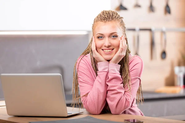ノート パソコンの横に座っている若い笑顔の女性 — ストック写真
