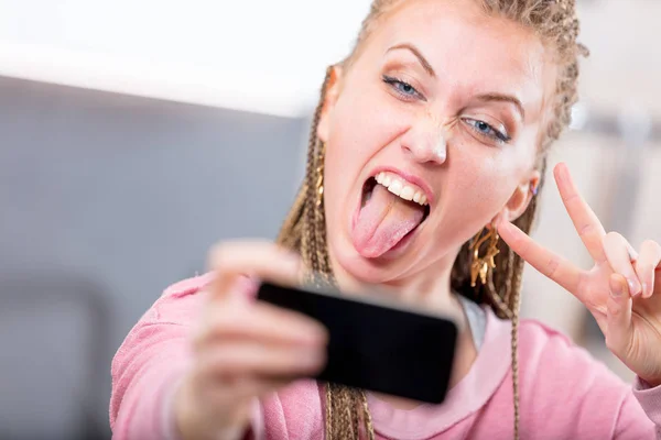 Jonge vrouw trekken een goofy gezicht voor een selfie — Stockfoto