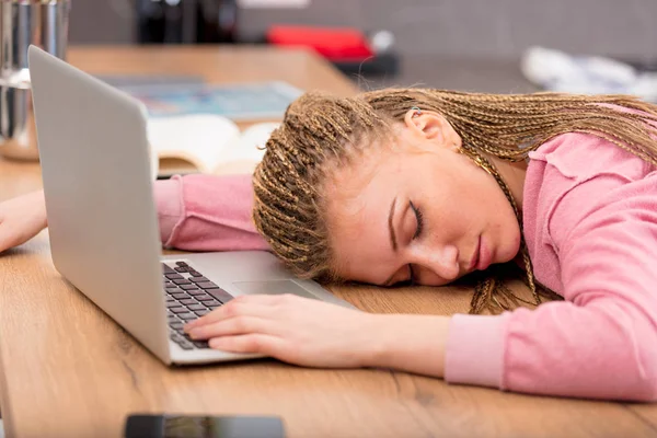 Exhausted young woman asleep at her laptop — Stock Photo, Image