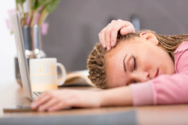 Tired attractive young woman sleeping on a table — Stock Photo, Image