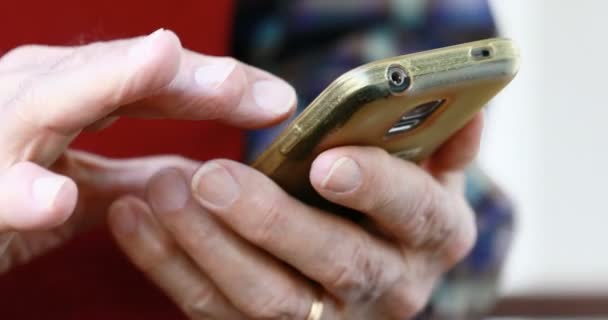 Close-up das mãos da pessoa idosa manuseando um smartphone — Vídeo de Stock
