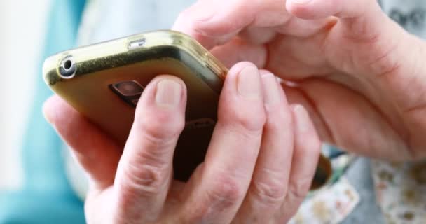 Close-up das mãos da pessoa idosa manuseando um smartphone — Vídeo de Stock