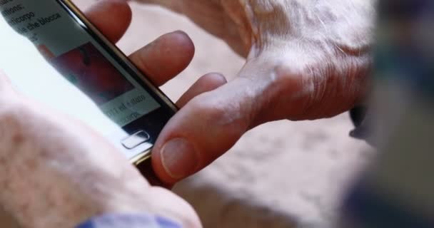 Close-up das mãos da pessoa idosa manuseando um smartphone — Vídeo de Stock