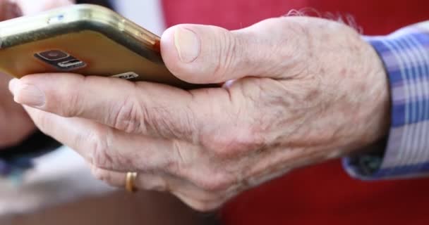 Primer plano de las manos de una persona mayor manejando un teléfono inteligente — Vídeo de stock