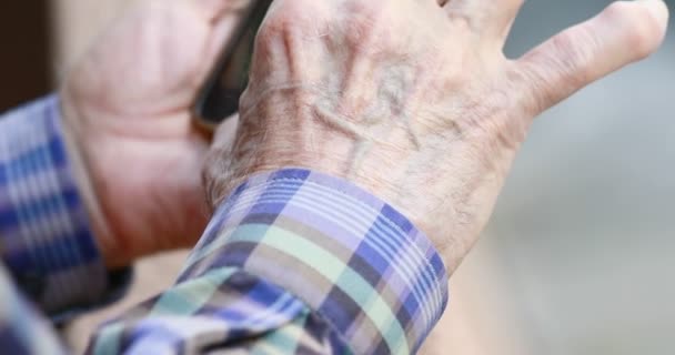 Close-up das mãos da pessoa idosa manuseando um smartphone — Vídeo de Stock