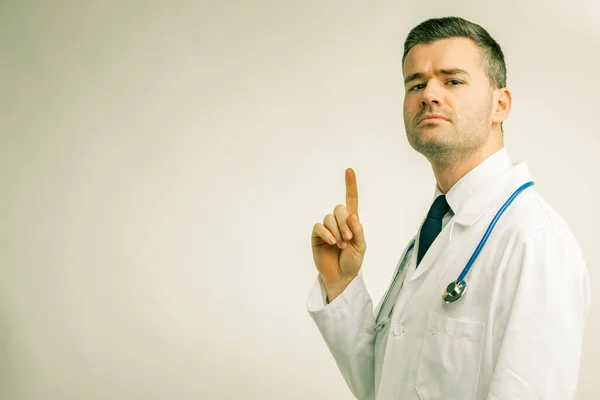 Mężczyzna Białym Płaszczu Stetoskopem Wskazując Palcem Wskazującym Pouczający Sposób Poważną — Zdjęcie stockowe