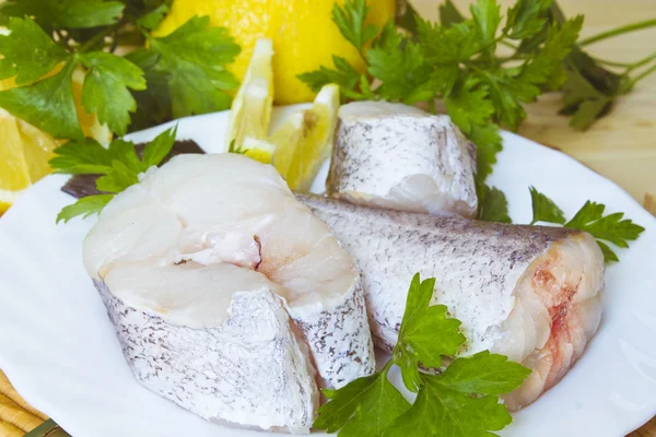 Hake dish with parsley and lemon on wooden background — Stock Photo, Image