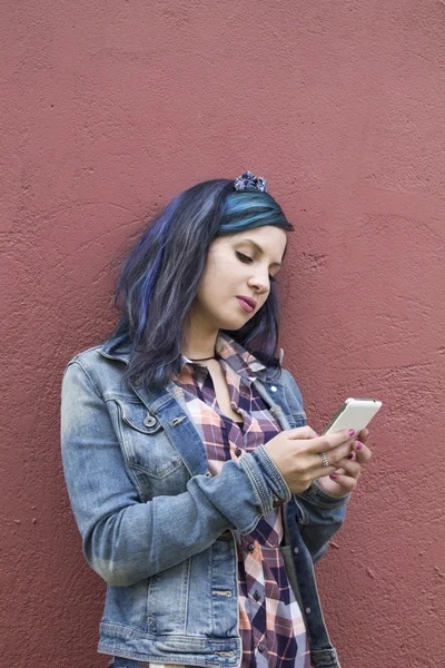 Young woman with mobile phone on the wall — Stock Photo, Image