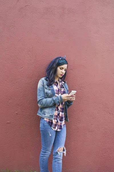 壁に携帯電話を持つ若い女性 — ストック写真