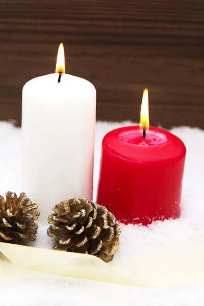 Tarjeta de Navidad con velas y piñas en la nieve —  Fotos de Stock